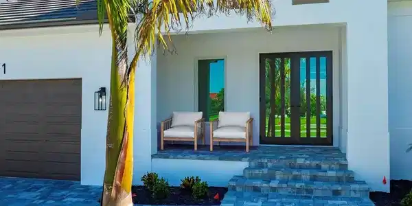 Image 3: Virtually Staged- View of exterior entry with stucco siding, french doors, and an attached garage