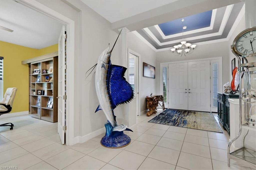 Image 2: Entrance foyer with a raised ceiling, a chandelier, crown molding, and light tile patterned floors