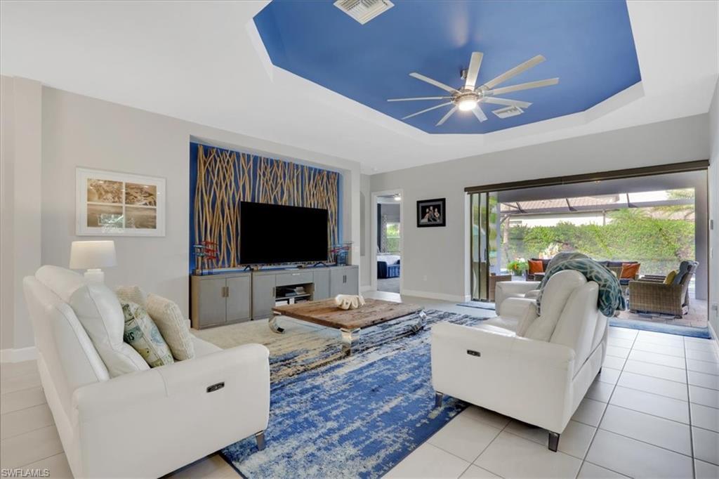 Image 4: Living room featuring a tray ceiling, a ceiling fan, and tile patterned floors