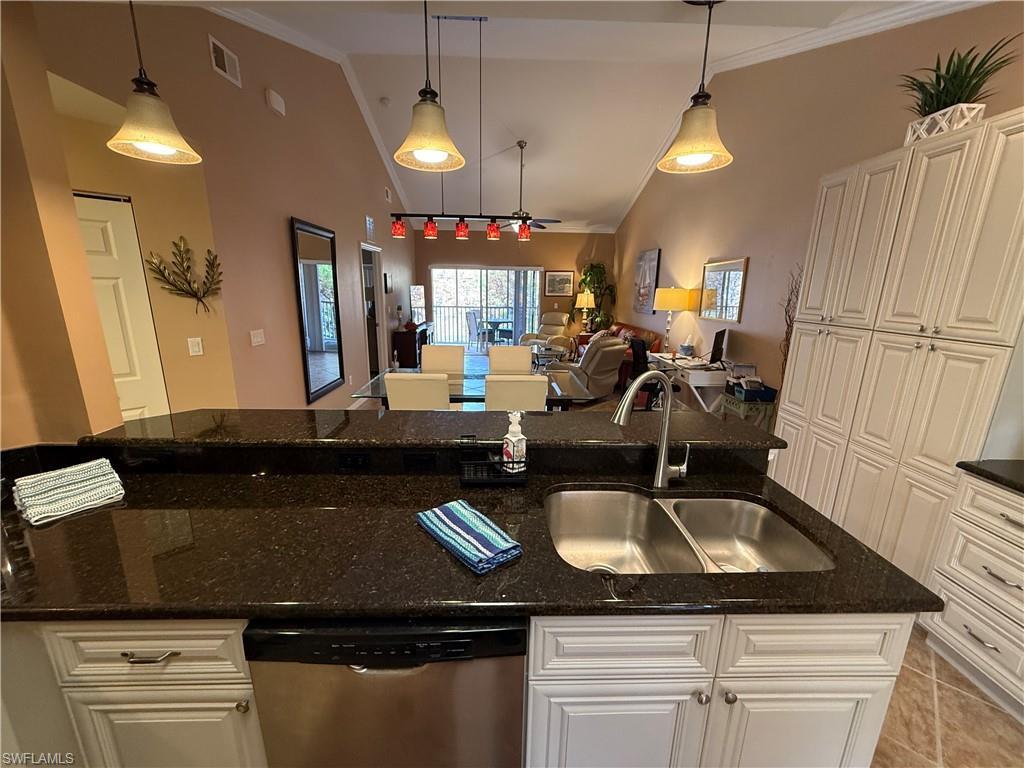 Image 4: Kitchen with lofted ceiling, pendant lighting, dishwasher, white cabinetry, and dark stone countertops