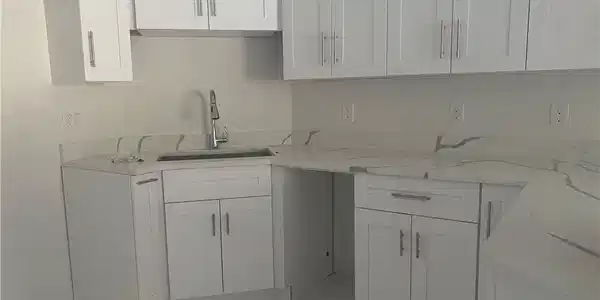 Image 3: Kitchen featuring light stone countertops and white cabinets