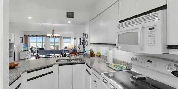 Image 4: Kitchen featuring white appliances, a chandelier, open floor plan, and white cabinets