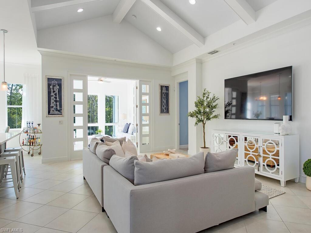 Image 2: Living room featuring light tile patterned flooring, beamed ceiling, high vaulted ceiling, and recessed lighting
