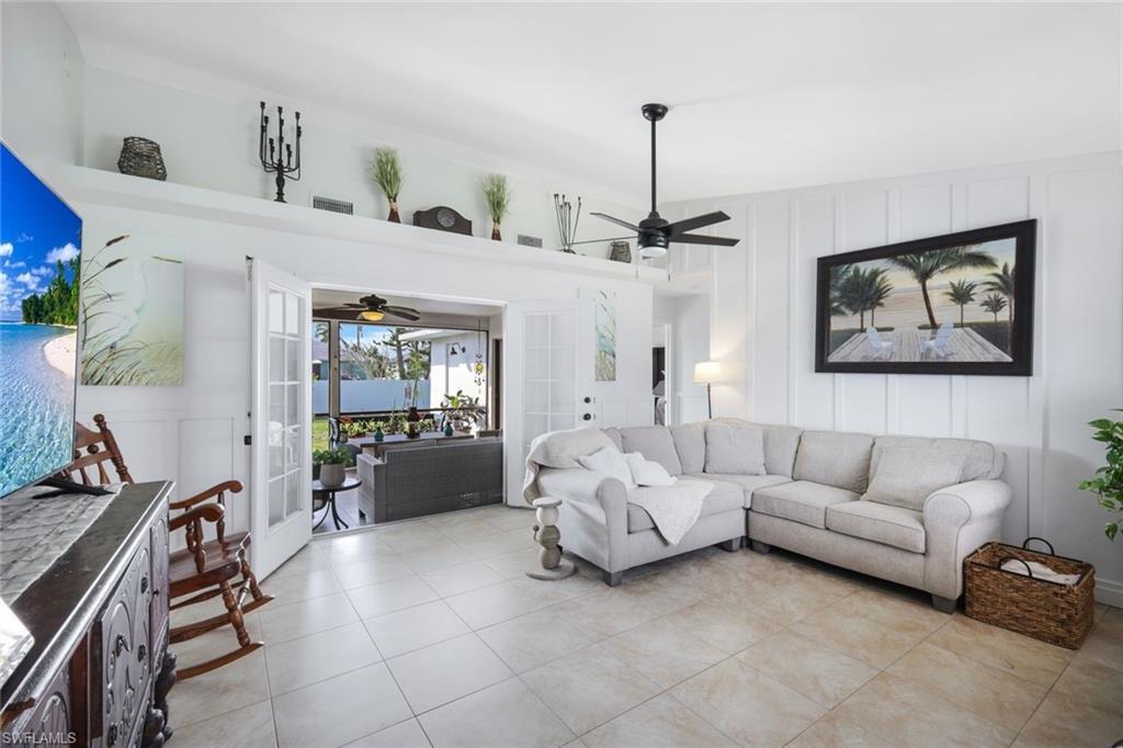 Image 3: Living area with a decorative wall, french doors, ceiling fan, light tile patterned flooring, and a high ceiling