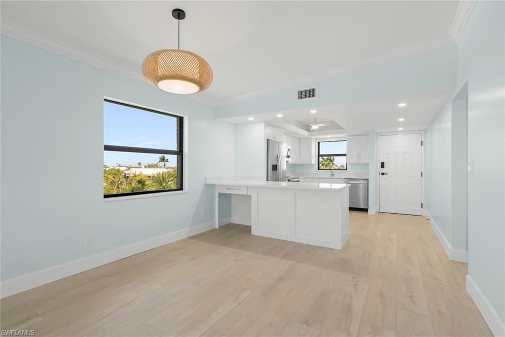Image 3: This open concept living space features light-colored flooring, light blue walls, and a contemporary light fixture