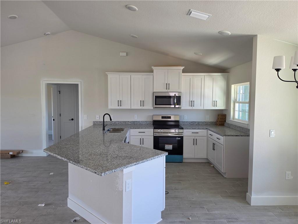 Image 3: Kitchen featuring white shaker cabinetry, stainless steel appliances, granite countertops, and a central island with an undermount sink