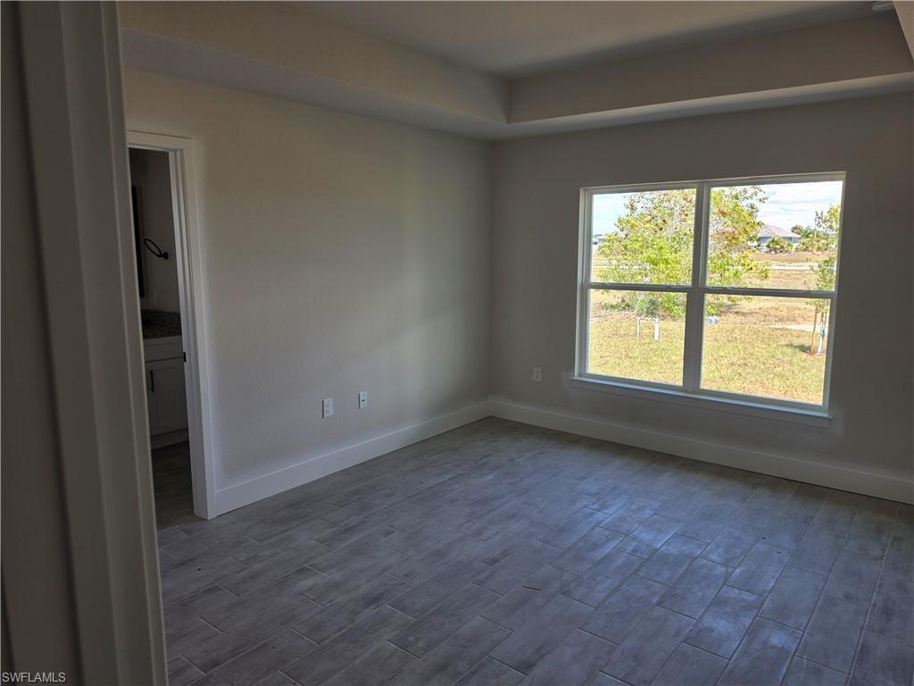 Image 4: Room featuring a tray ceiling, tile flooring, and a large window with white trim