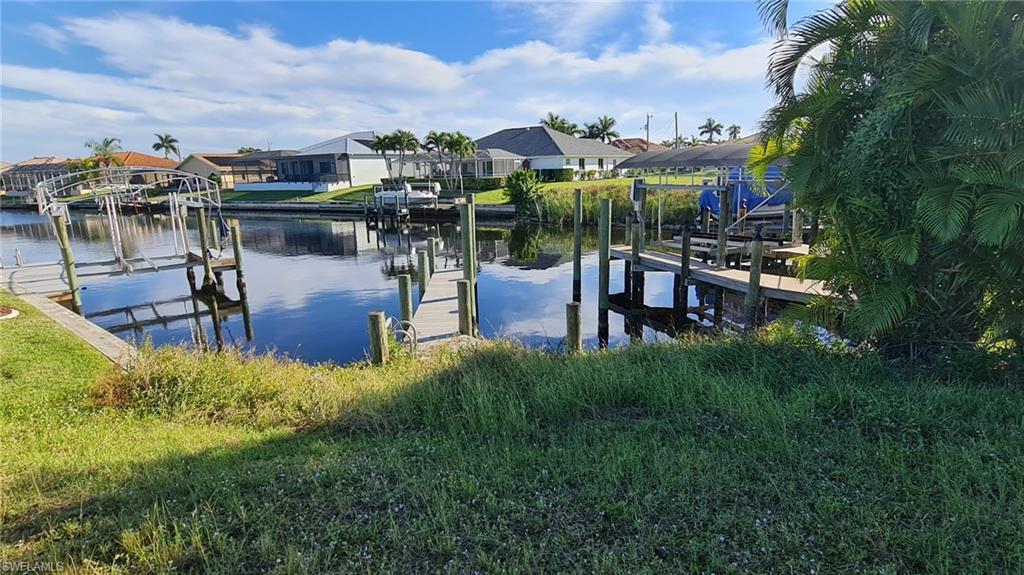 Image 3: Dock featuring a water view, boat lift, and a residential view