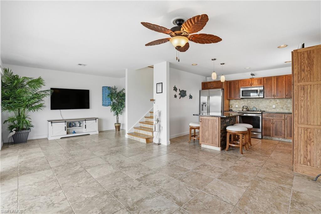 Image 2: Kitchen with a center island, stainless steel appliances, a ceiling fan, pendant lighting, and a breakfast bar