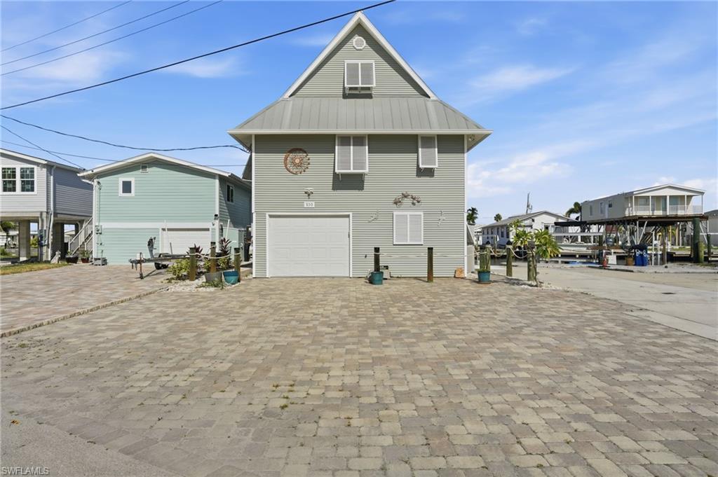 Image 3: Back of property with a garage, driveway, a metal roof, and a residential view
