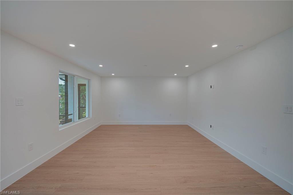 Image 4: Spacious room featuring wood-finish flooring, recessed lighting, and white baseboards