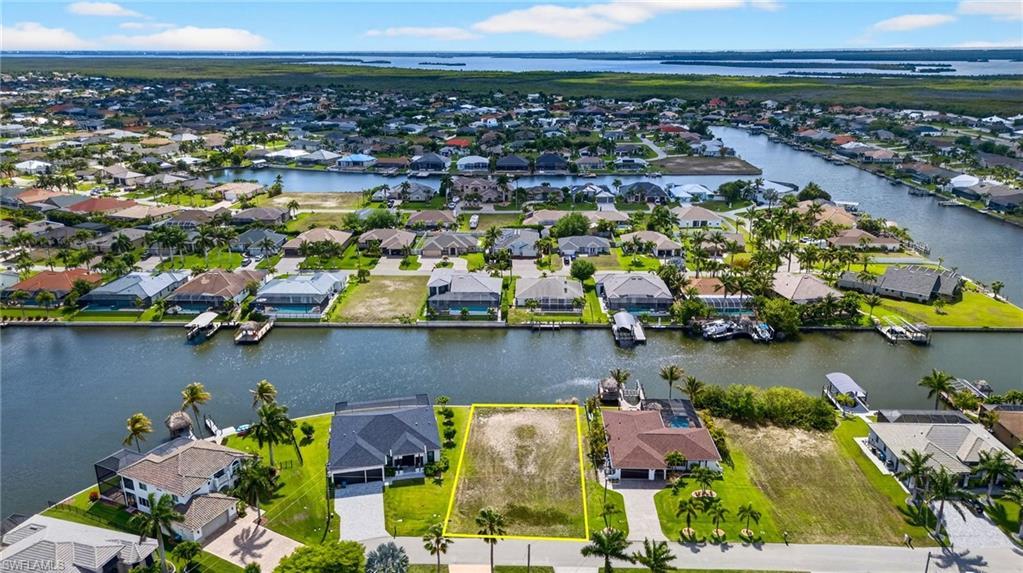 Image 2: Aerial view of residential area with property parcel outlined and a large body of water