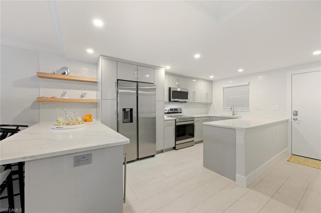 Image 1: Kitchen with a peninsula, a breakfast bar area, stainless steel appliances, open shelves, and recessed lighting