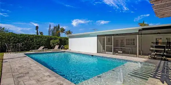 Image 4: View of pool with patio surround and a sunroom