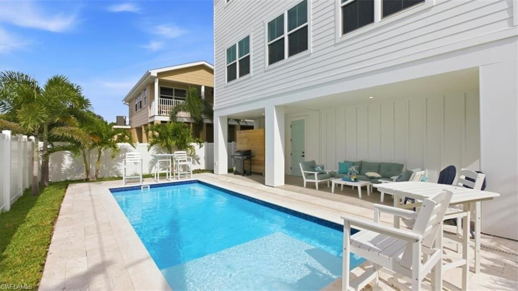 Image 2: View of pool with a balcony, an outdoor lounge area, a fenced backyard, patio surround, and a grill - Virtually Edited