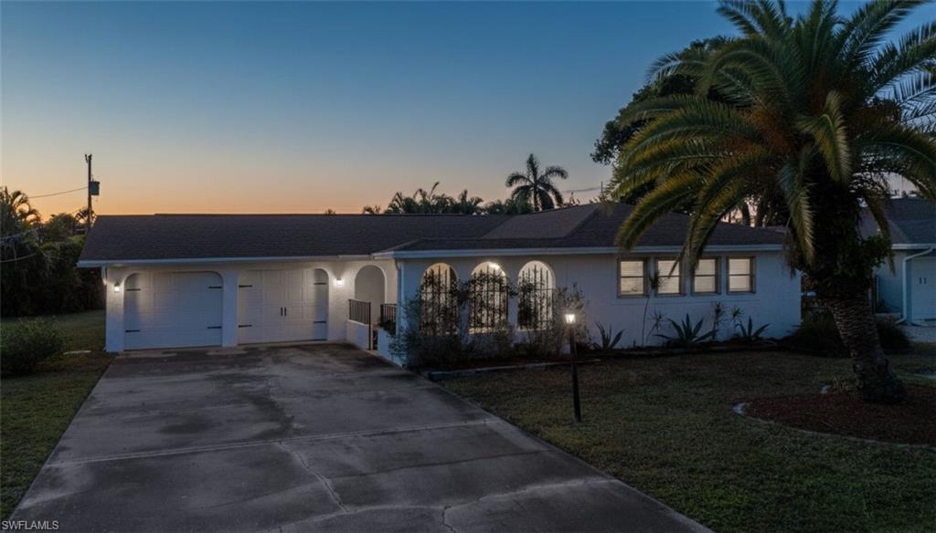 Image 2: View of front of home featuring concrete driveway, stucco siding, a front lawn, and a garage
