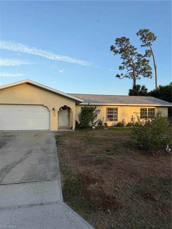 Image 2: Ranch-style home with stucco siding, concrete driveway, a garage, and a front lawn