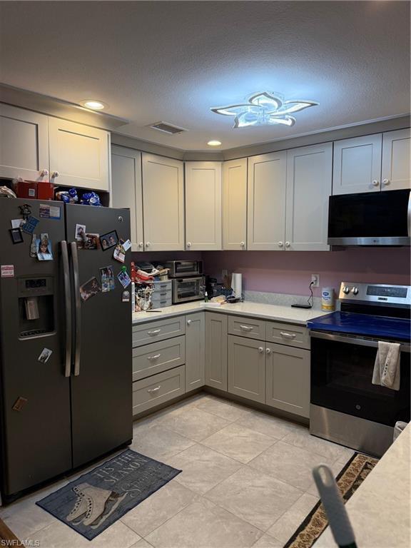 Image 4: Kitchen featuring refrigerator, stove, gray cabinetry, a textured ceiling, and recessed lighting