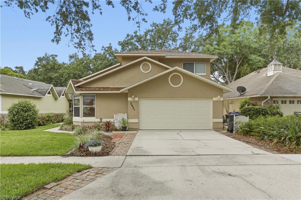 Image 4: Two-story stucco home featuring a two-car garage, concrete driveway, and front lawn with mature landscaping