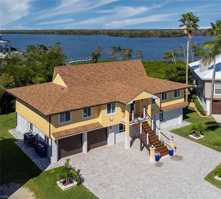 Image 1: View of front of elevated house featuring a garage, a shingled roof, stucco finishes, and a huge decorative driveway