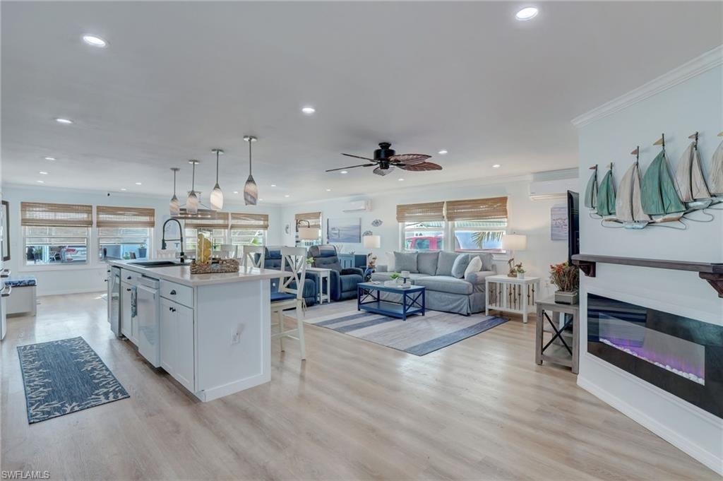 Image 4: Kitchen with open floor plan, a glass covered fireplace, a breakfast bar, light wood-type flooring, and a center island with sink