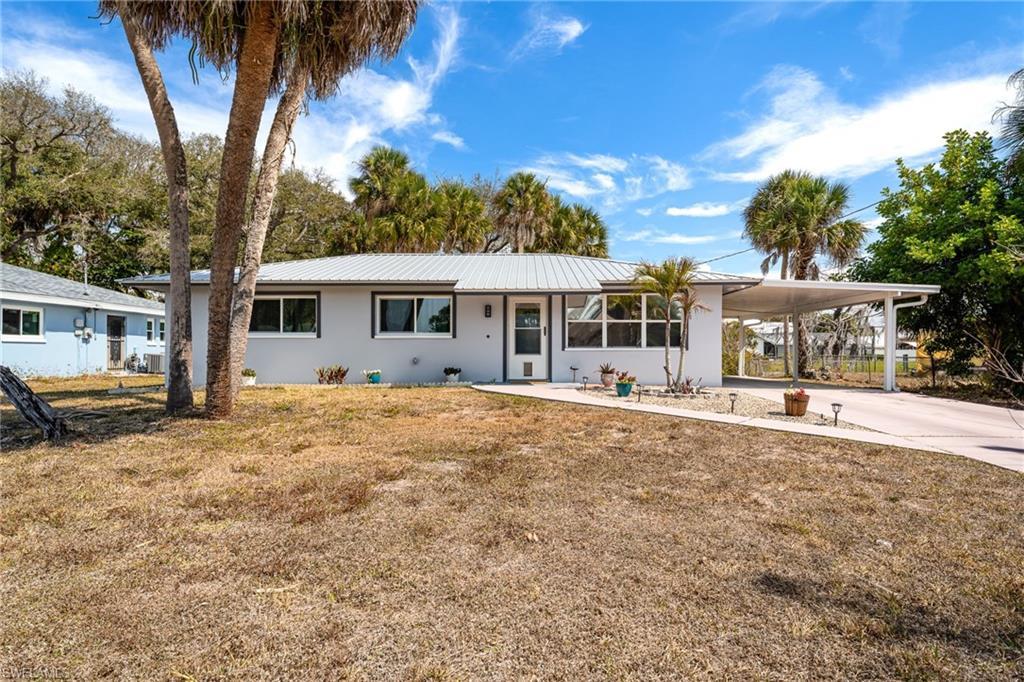 Image 2: Ranch-style home with a carport, driveway, a front yard, and stucco siding