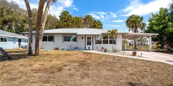 Image 2: Ranch-style home with a carport, driveway, a front yard, and stucco siding