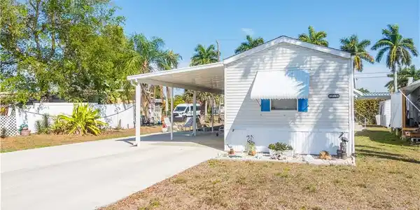 Image 3: View of home's exterior featuring an attached carport, concrete driveway, and a lawn