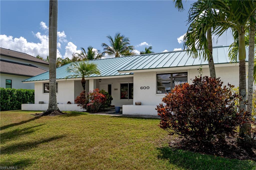 Image 2: Ranch-style house with a standing seam roof, stucco siding, and a front lawn