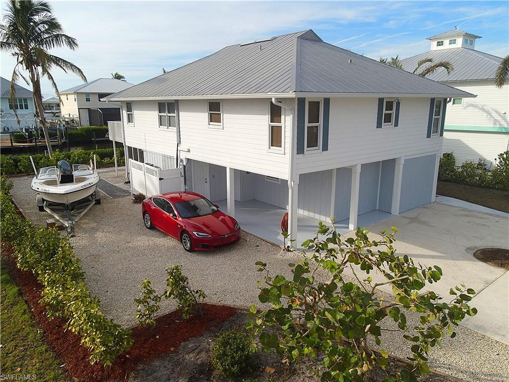 Image 1: Back of property featuring a garage, a metal roof, and driveway
