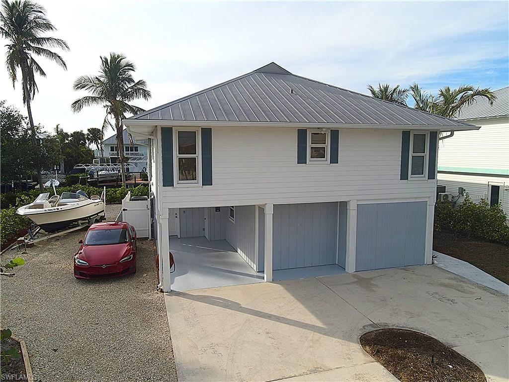 Image 2: View of front facade with a metal roof, concrete driveway, and a garage