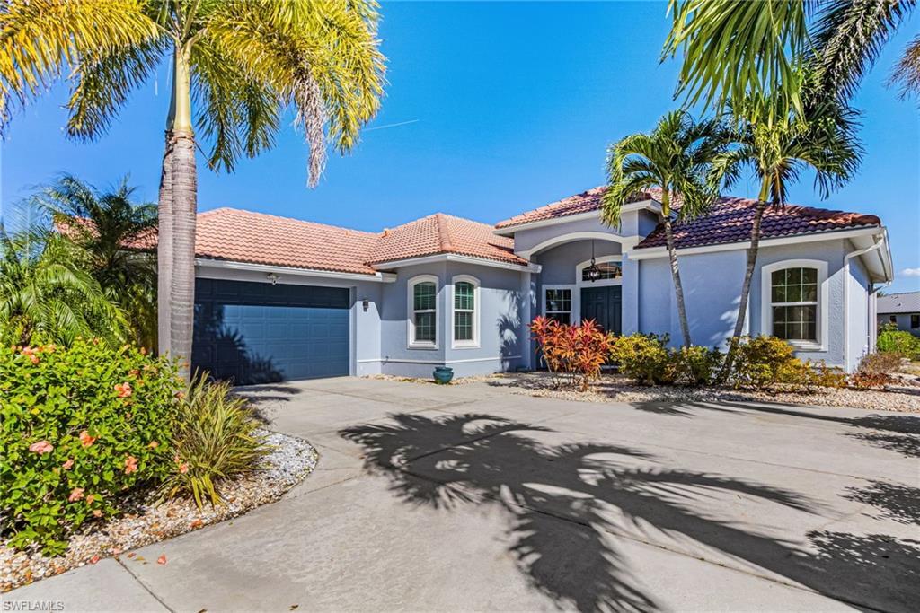 Image 1: The property features a concrete driveway, a tile roof, an attached garage, and tropical landscaping with palm trees