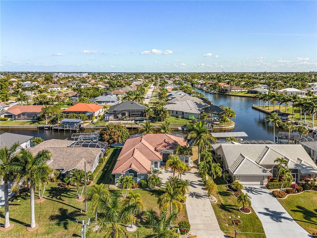 Image 2: Aerial view showcasing the property's location along a canal, surrounded by mature palm trees and residential properties