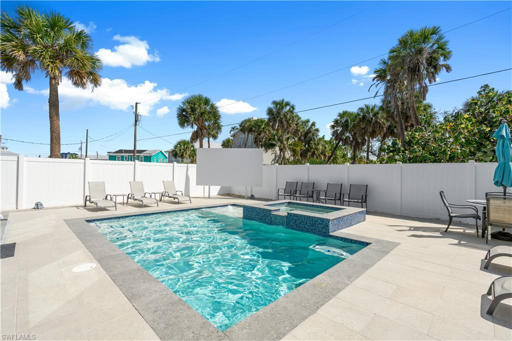 Image 3: Outdoor entertainment area featuring an in-ground swimming pool, an integrated spa with blue mosaic tiling, and extensive light-toned paver decking