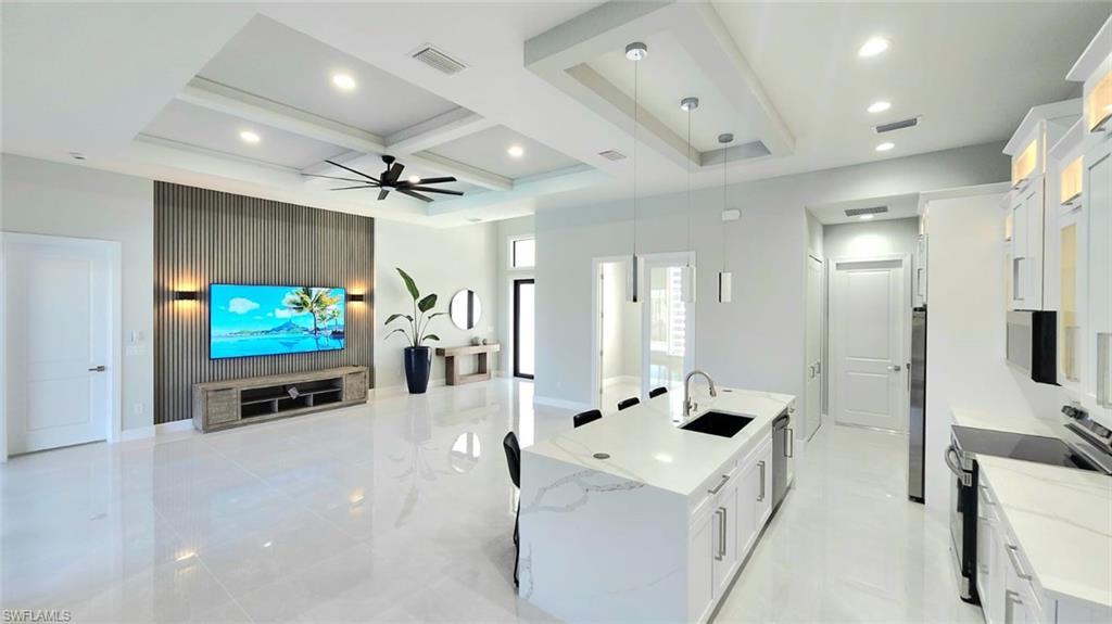 Image 4: Kitchen featuring a spacious island, white cabinetry, open floor plan, stainless steel appliances, and coffered ceiling