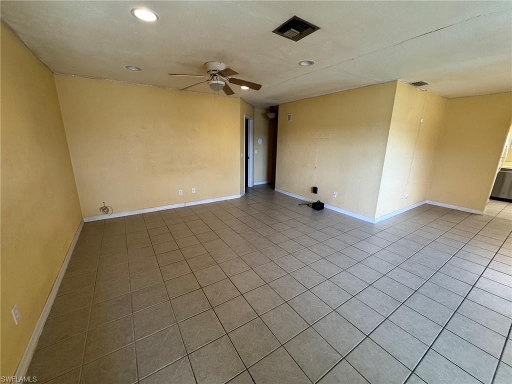 Image 4: Spacious living room featuring neutral-toned tile flooring, recessed ceiling lighting, and a ceiling fan with integrated illumination
