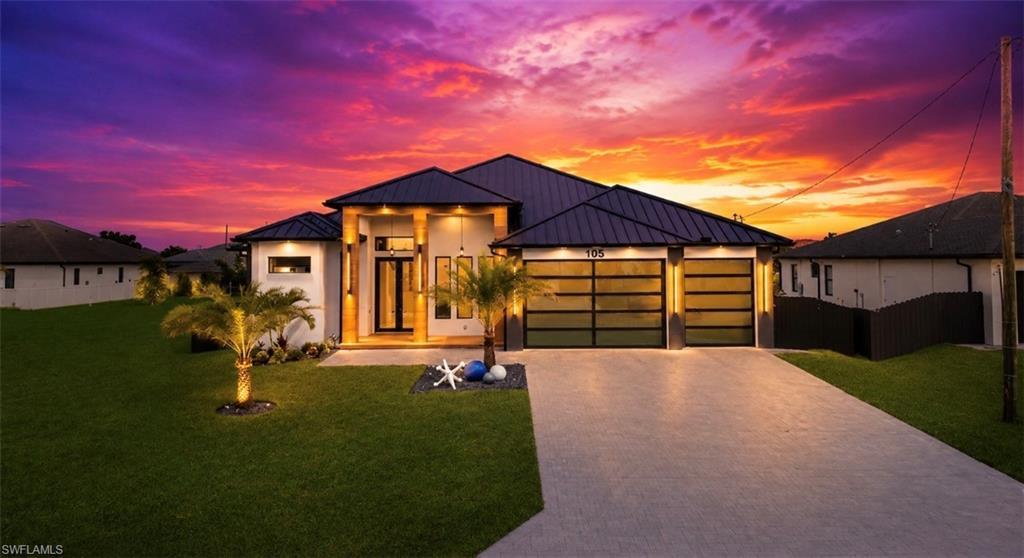 Image 1: Contemporary architecture featuring a dark metal roof, clean white exterior, two-car garage with frosted glass doors, a paver driveway, and a manicured lawn with palm trees