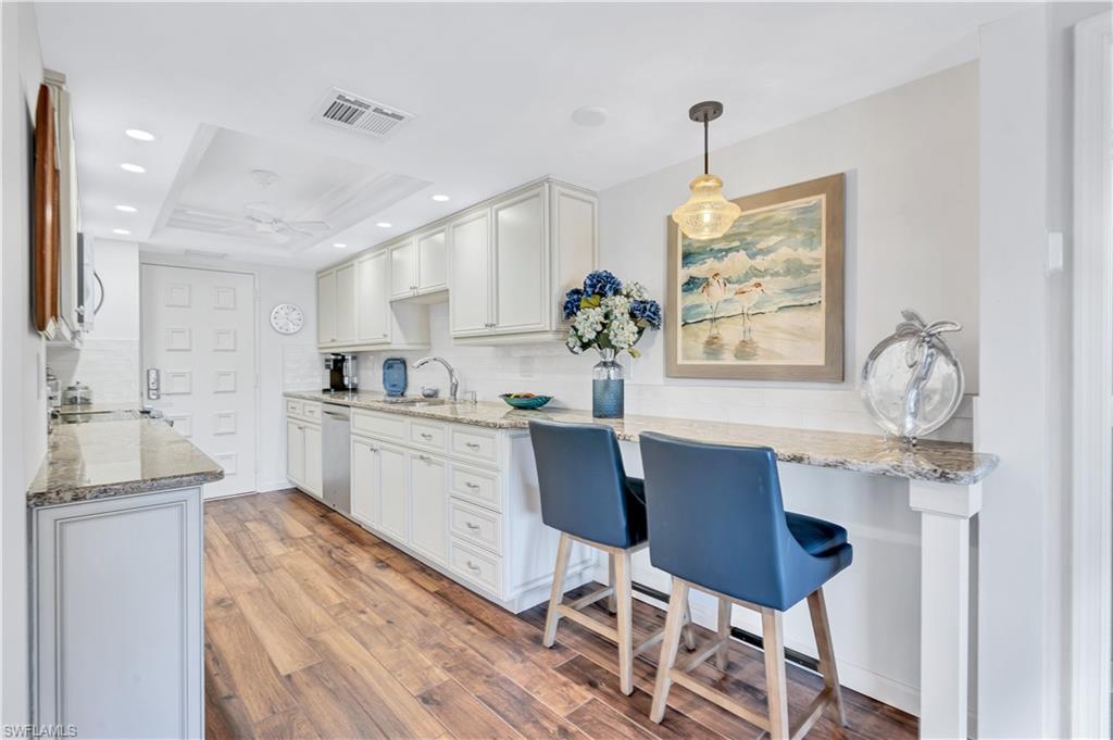 Image 4: Kitchen featuring tasteful backsplash, light wood-type flooring, light stone countertops, white cabinetry, and recessed lighting