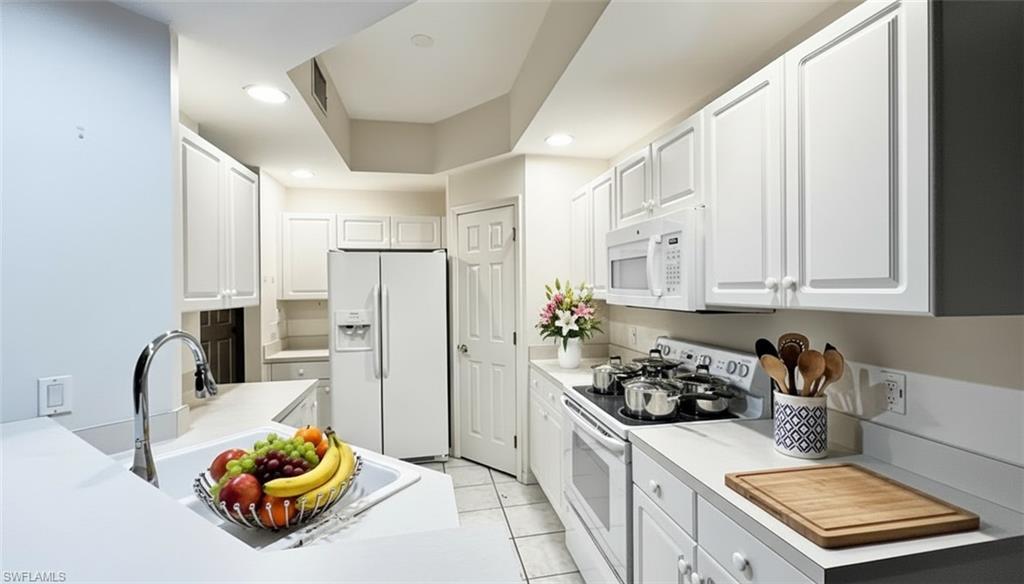 Image 3: Kitchen with white appliances, white cabinetry, light countertops, recessed lighting, and light tile patterned floors