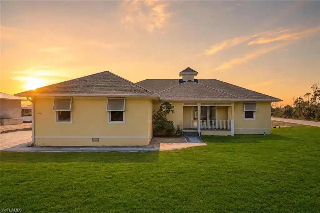 Image 1: Single-story residence featuring a covered entry, screened porch, cupola detail, and mature landscaping