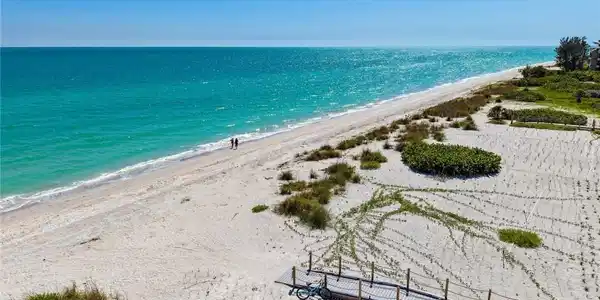 Image 3: Expansive beachfront featuring white sand, turquoise waters, and natural dunes
