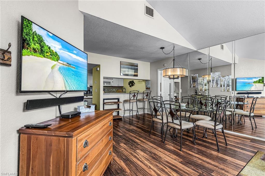 Image 2: Dining room featuring dark wood finished floors, a textured ceiling, and vaulted ceiling