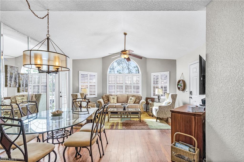 Image 3: Dining room featuring lofted ceiling, a ceiling fan, wood finished floors, a chandelier, and a textured ceiling