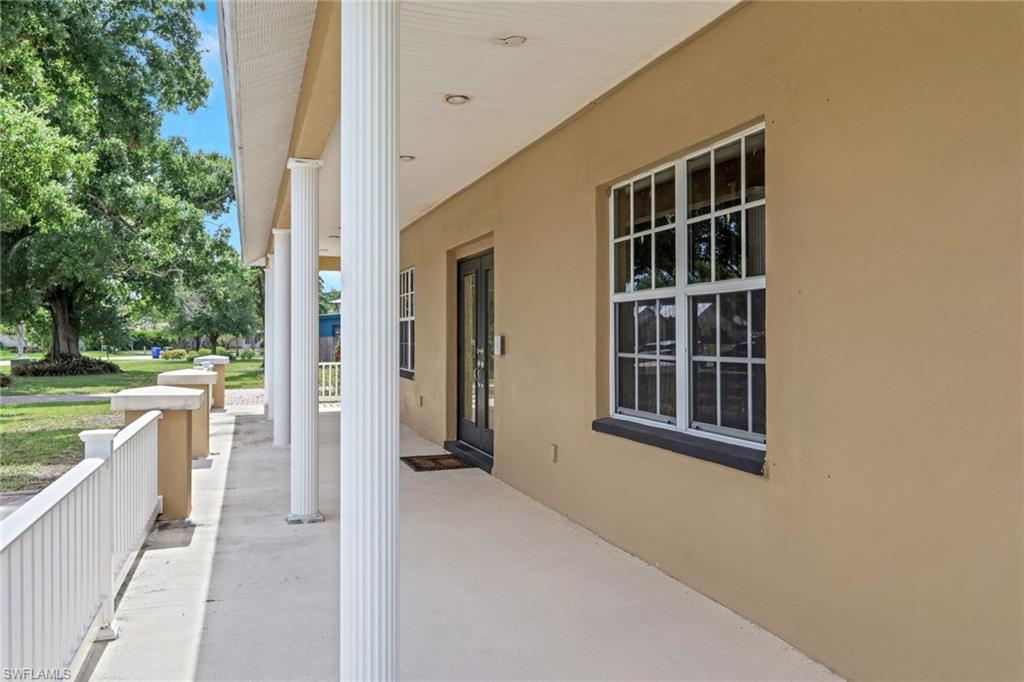Image 4: Exterior facade featuring a covered porch with white fluted columns, a concrete walkway, and a white railing system