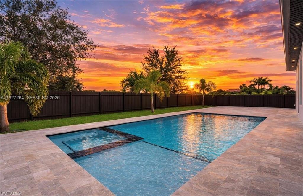 Image 3: Expansive backyard featuring a rectangular swimming pool with an integrated spa, surrounded by large format stone-finish patio tiles