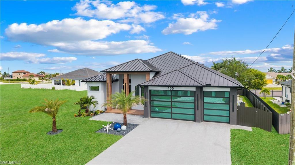 Image 4: Contemporary residence featuring a metal roof, two modern glass garage doors, and a concrete driveway