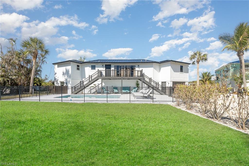 Image 2: Expansive backyard featuring a manicured lawn, a fenced swimming pool, and a raised exterior deck with dual staircases