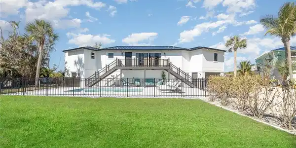 Image 2: Expansive backyard featuring a manicured lawn, a fenced swimming pool, and a raised exterior deck with dual staircases