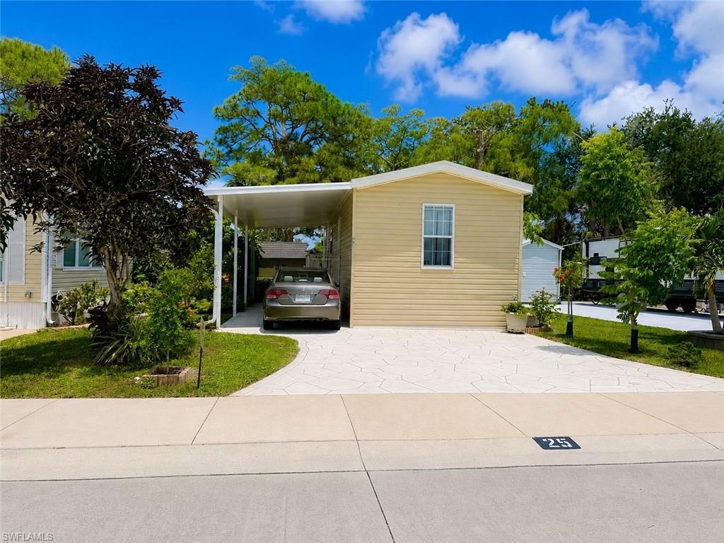 Image 1: Single-story residence featuring light yellow siding, white trim, and a white carport