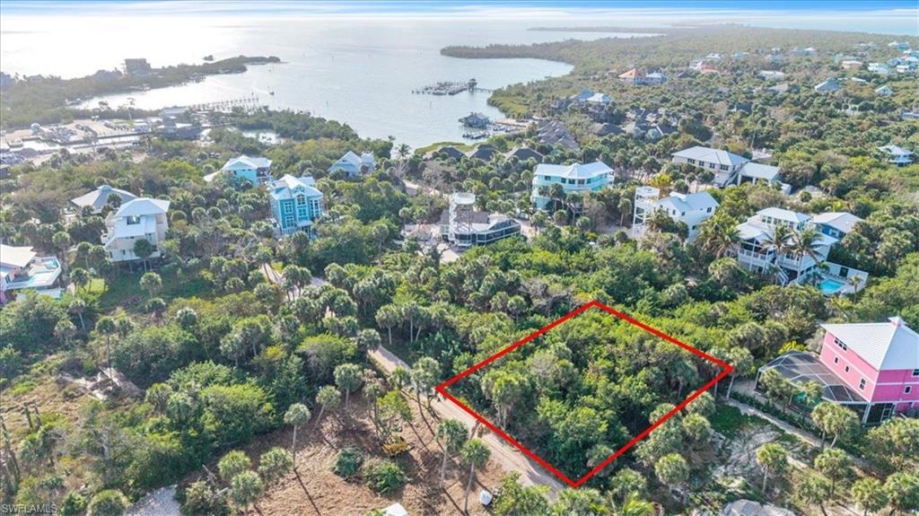 Image 3: Aerial view of lot (outlined in red) with North Captiva's harbor and marina visible &mdash; boat in, step off, and walk home. Island life doesn't get more convenient than this.